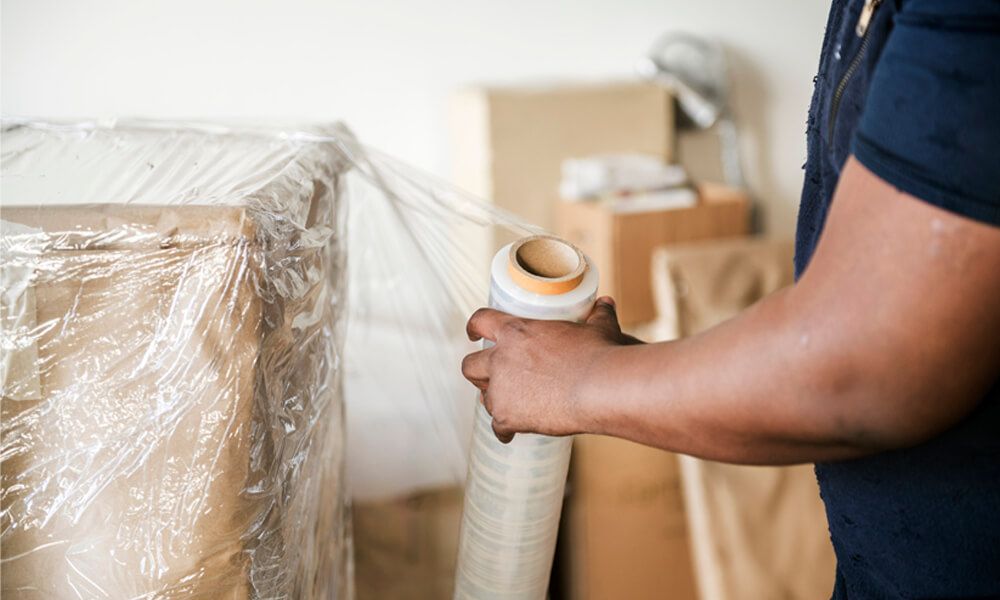 man using pallet wrap to move furniture