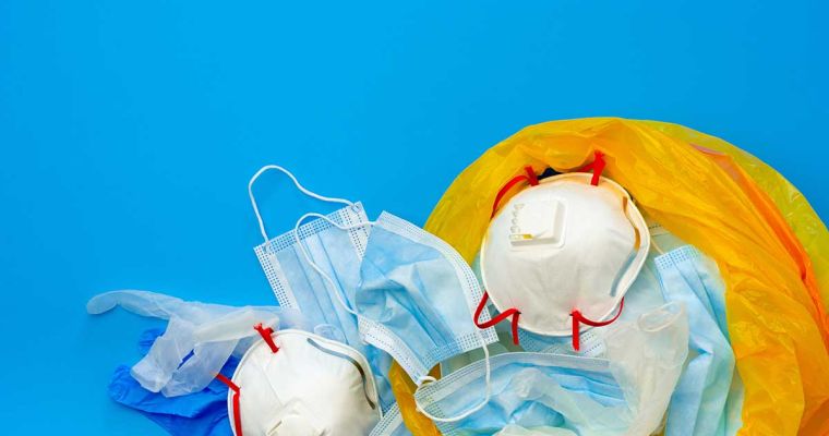 Protective equipment masks gloves in a orange clinical waste bag
